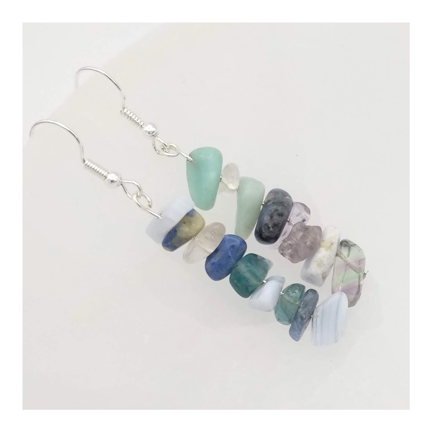 Assorted chipped crystals including sodalite, blue lace agate, amazonite, clear quartz and green fluorite. Hanging on a silver toned fishhook, with the gemstones a-lined on a 2 1/4th inch drop in a random but complementary order.
