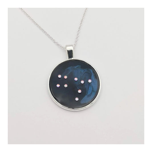 Dark blue with iridescent sparkling swirls of pinks, purples, silver, and monochromatic shades of blue enamel. With handset Aurora Borealis rhinestones to represent the star of the constellation of Gemini. The pendant is 1 inch silver toned with a 1/4th inch bail on a silver toned chain.