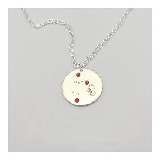 July Leo necklace pendant with hand set ruby colored glass rhinestones forming the constellation of Leo. Hand stamped with the zodiac symbol for Leo, on a 3/4th of an inch silver toned circle hanging from a silver toned chain.