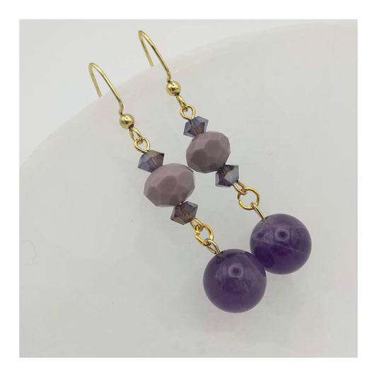 Amethyst, monochromatic purple and iridescent beads a-lined on a 2 inch drop earring on gold toned fish hooks. 