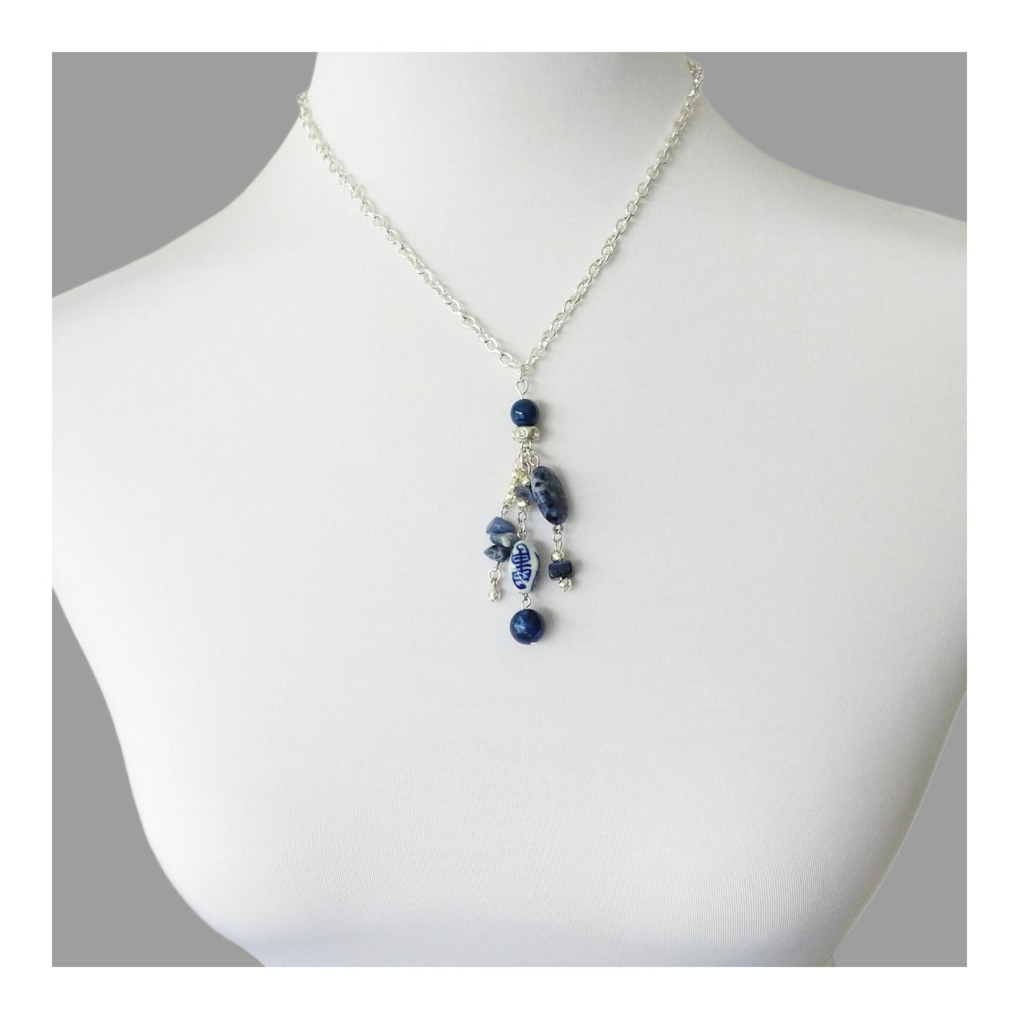 Silver toned 16 inch chain adorn with 3 inch drop hand strung tassel with oval and chipped sodalite, round lapis lazuli, oblong white and blue porcelain and other assorted blue and silver toned beads.  