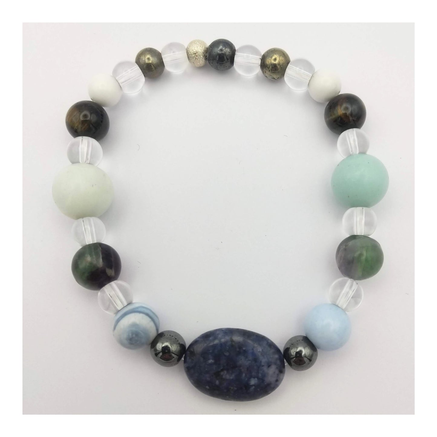 Mercury retrograde elastic bracelet with an oval blue sodalite bead at the center with other crystals such as blue lace agate, clear quartz, green and purple fluorite and other gemstones in a symmetrical pattern. In soothing cool tones along with hematite and pyrite which have a metallic finish.