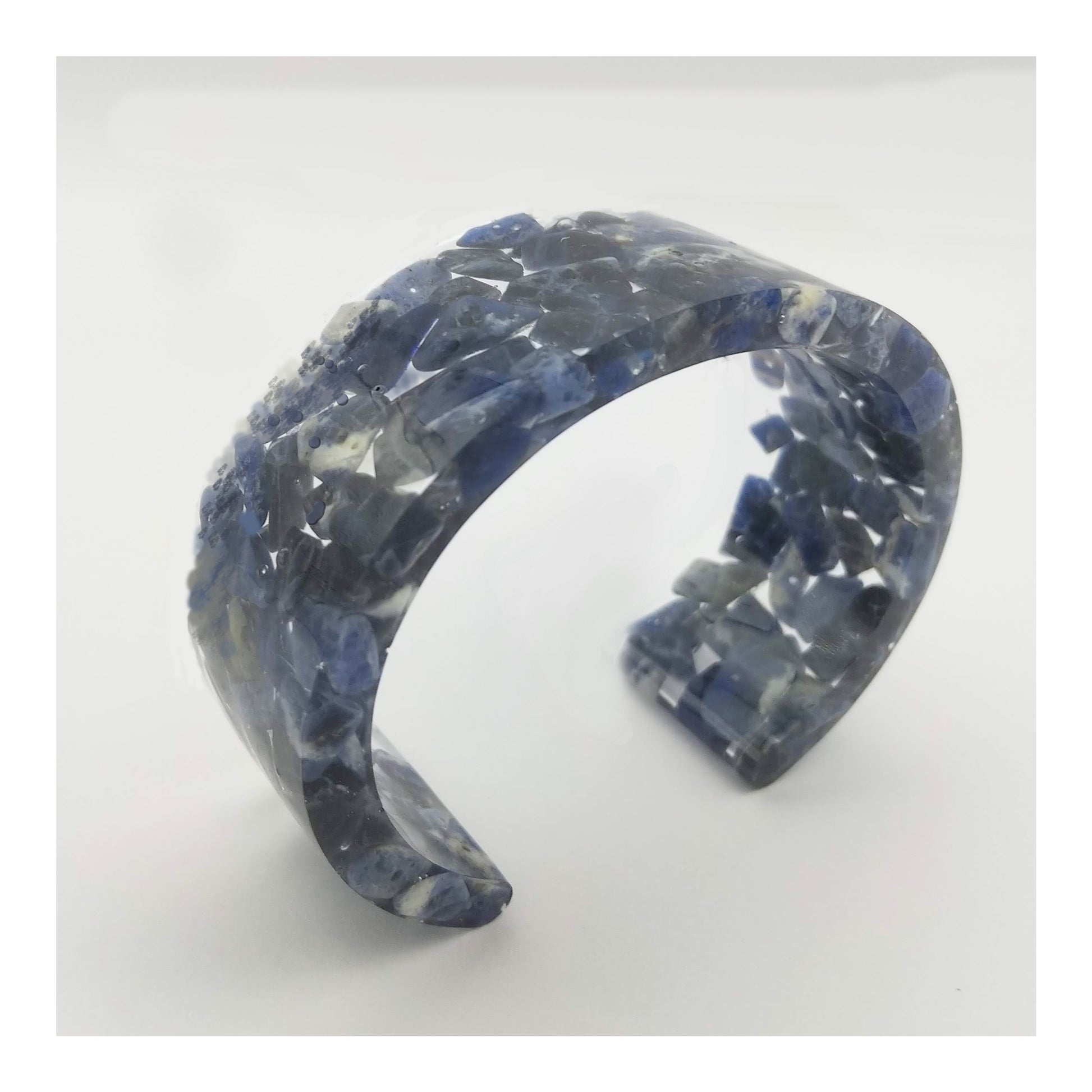 Blue and white sodalite chips encased in clear resin to form a 1 inch and ¼ inch thick cuff bracelet. 