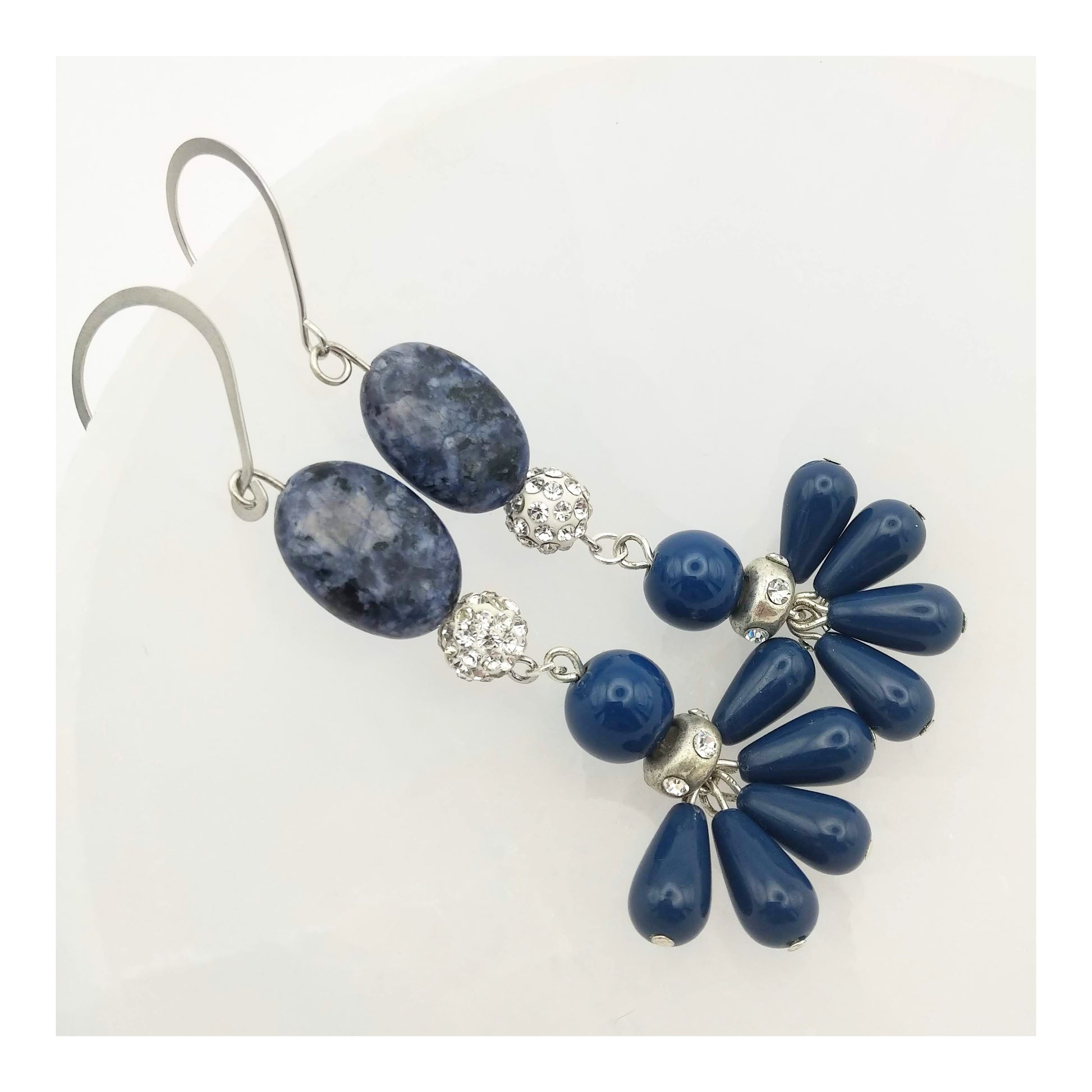 Blue and white flat oval sodalite bead with a clear round rhinestone bead connected to a round blue bead with matching teardrop tassel with even more rhinestones between the round and tassel charms for extra sparkle. Hanging on a silver toned fish hook drop. These earrings hang 3 ¼ inches. 